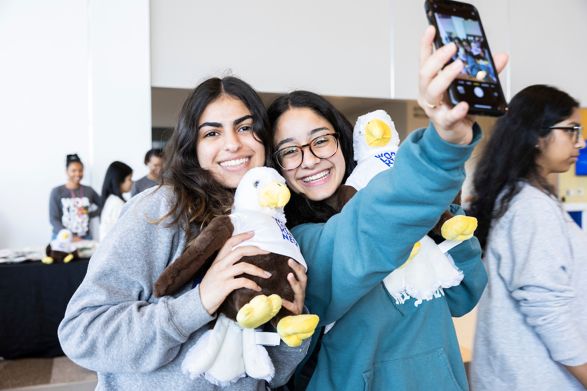 Students taking a selfie with plushie Swoop